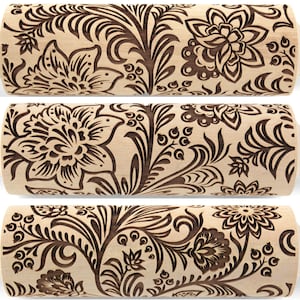 May include: A wooden rolling pin with a floral design engraved into the surface. The design features intricate swirls and leaves in a dark brown color.