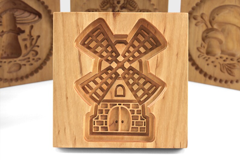 Puede incluir: Un cortador de galletas de madera con forma de molino de viento. El cortador est&aacute; hecho de madera marr&oacute;n claro y tiene un dise&ntilde;o detallado.