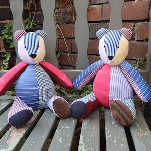 May include: Two patchwork teddy bears sitting on a wooden bench. The bears are made from different fabrics in shades of blue, red, and white. They have black eyes and noses.
