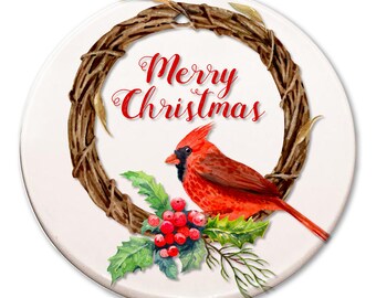 May include: A round Christmas ornament with a red cardinal bird perched on a branch with red berries and green leaves. The ornament has a brown twig wreath with the words "Merry Christmas" in red lettering.
