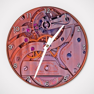 May include: A round clock face with exposed watch gears and mechanisms. The clock features white hands, a copper-colored frame, and visible gears in shades of gold and silver. The face displays the numbers 1 through 12 and text that reads "EXTRA" and "TWENTY ONE (21) JEWELS".
