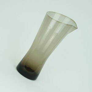 May include: A brown glass pitcher with a flared top and a rounded base.