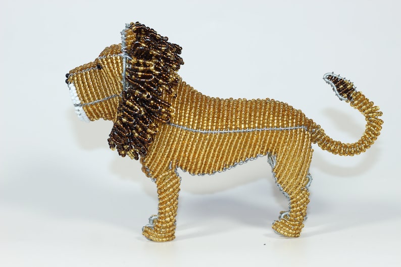 May include: A beaded lion figurine with a golden body and a brown mane. The lion is standing on all four legs with its tail curled up.