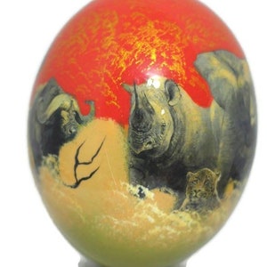 May include: A hand-painted ostrich egg with a red background and gold accents. The egg features a scene of a rhinoceros, a buffalo, and a leopard in a savanna setting.