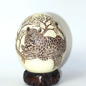Brullende luipaard op een boomtop geschilderd scrimshaw-struisvogeleischaalornament met houten standaard. Uniek huisdecoratiecadeau Afrikaanse kunst, klaar voor verzending