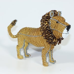 May include: A beaded lion figurine with a gold and brown mane. The lion is standing on all four legs and has a long tail.