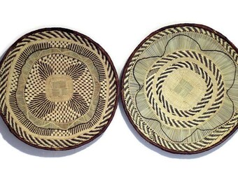 May include: Two round woven baskets with brown and white patterns. The baskets are made of natural materials and have a rustic look.