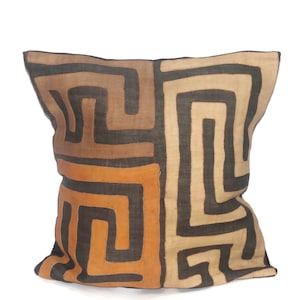 May include: Square decorative pillow with a geometric pattern in shades of brown, tan, and orange. The pillow features a repeating maze-like design. The pillow is made of a textured fabric and is suitable for home decor.