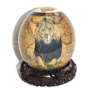 Decoupage met struisvogelei Voorwaarts gerichte volwassen Lion King op een bruine Afrikaanse kaartachtergrond. Wordt geleverd met een houten standaard. Kunstcadeau klaar voor verzending