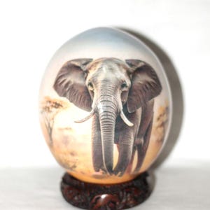 Vorderseite gehende Elefant-Decoupage-Kunst auf authentischer Straußenei-Schale, mit Holzständer. Brown-Hintergrund und blauer Himmel afrikanischer Geschenkdekor
