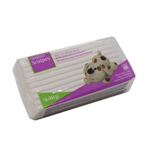 Pode incluir: Um bloco de argila para assar Sculpey Original branco de 454 gramas. A embalagem apresenta um cão de desenho animado e o texto "Fica macia até assar!"