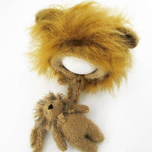 Puede incluir: Un gorro de punto marr&oacute;n en forma de le&oacute;n con una melena esponjosa y un juguete de punto marr&oacute;n a juego en forma de le&oacute;n.