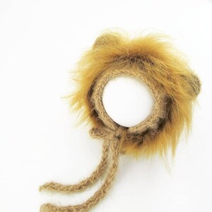 Puede incluir: Un gorro de punto marr&oacute;n con forma de le&oacute;n con una melena esponjosa y dos lazos largos. El gorro est&aacute; dise&ntilde;ado para un beb&eacute; o reci&eacute;n nacido.