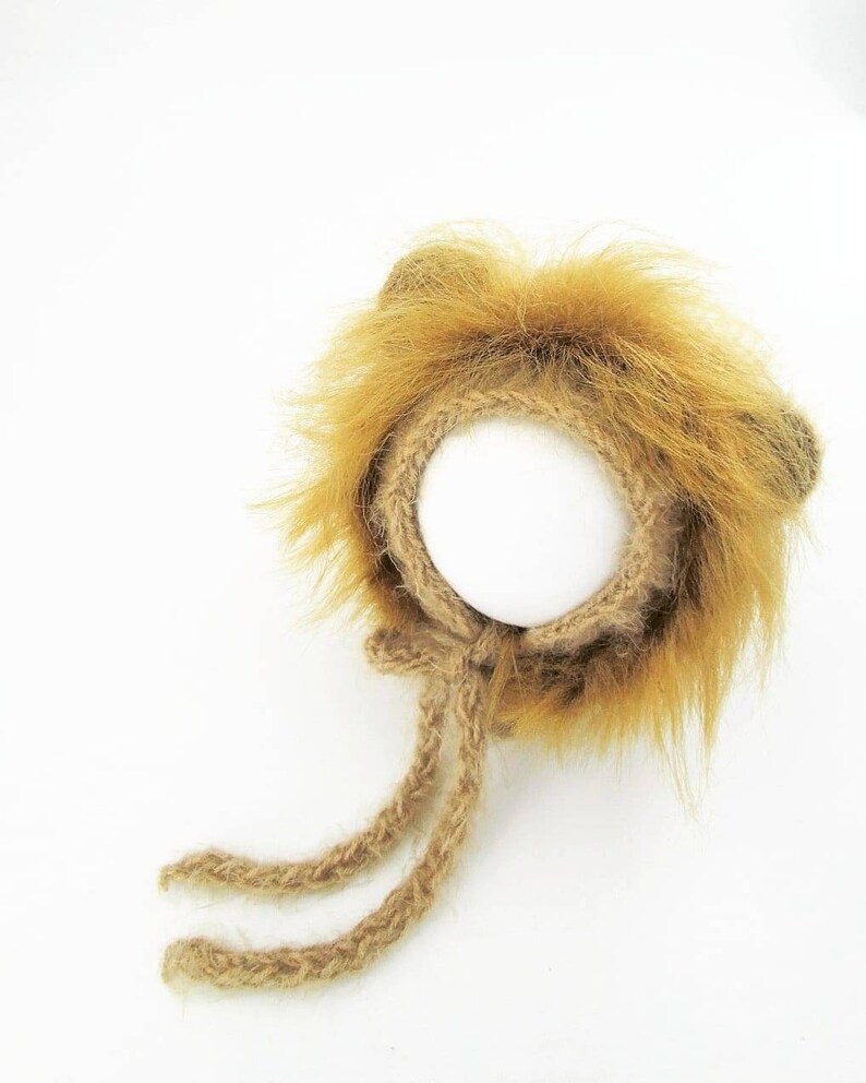 Puede incluir: Un gorro de punto marr&oacute;n con forma de le&oacute;n con una melena esponjosa y dos lazos largos. El gorro est&aacute; dise&ntilde;ado para un beb&eacute; o reci&eacute;n nacido.