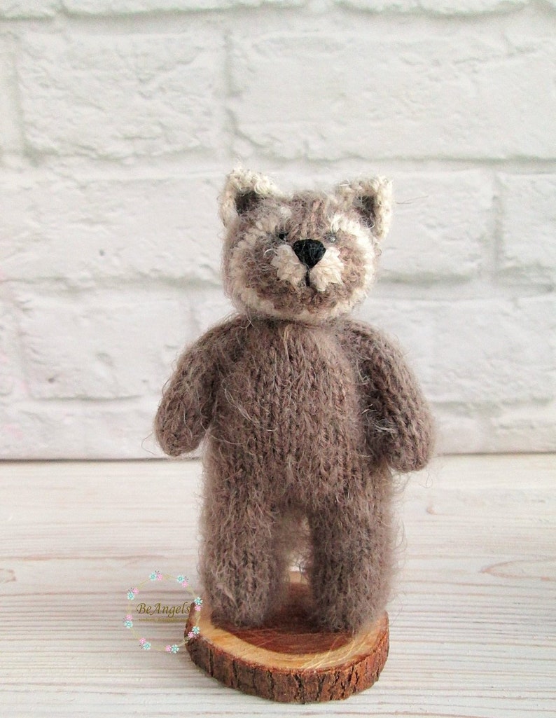 Peut inclure: Un petit jouet en peluche en tricot marron en forme de raton laveur. Le jouet est debout sur une tranche de bois.