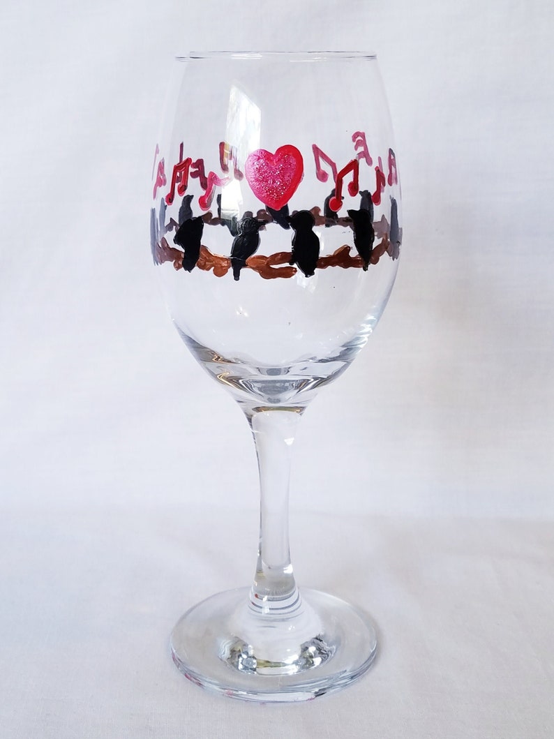 Wine glass features hand painted love birds on a brown branch with black birds and a red heart It make a lovely gift for any occasion!