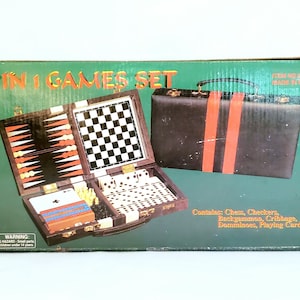May include: A 6 in 1 games set in a brown leatherette case with a red stripe. The case opens to reveal a chessboard, backgammon board, cribbage board, dominoes, and playing cards. The box is green with the text "6 in 1 Games Set" in red and yellow.