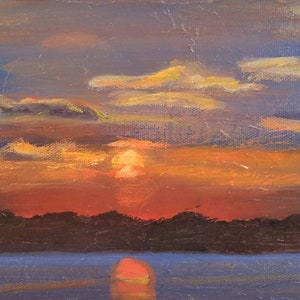 Original sunset painting in beautiful shades of blue, orange, purple and yellow is peaceful. The setting sun is reflected in the water.