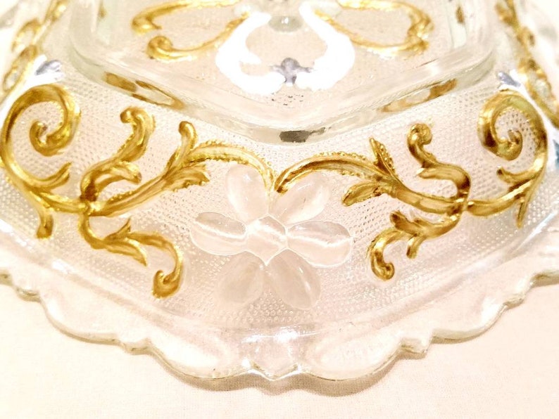 6 sided glass bowl has clear glass flowers silver and white heart shapes and raised dot designs. Scalloped edge gold embellished vines