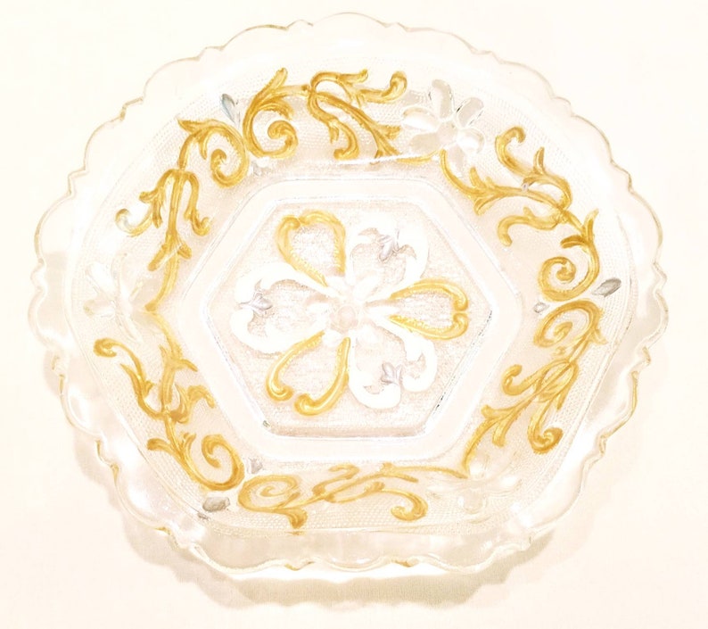 6 sided glass bowl has clear glass flowers silver and white heart shapes and raised dot designs. Scalloped edge gold embellished vines
