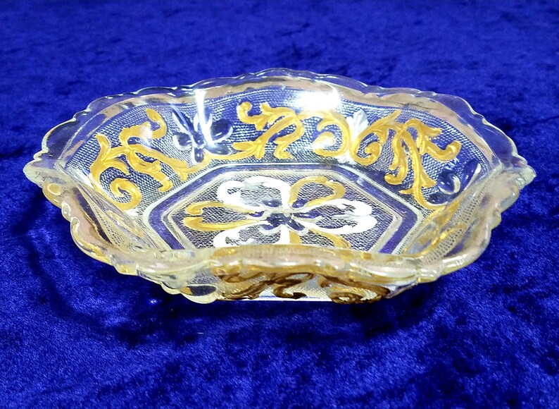 6 sided glass bowl has clear glass flowers silver and white heart shapes and raised dot designs. Scalloped edge gold embellished vines