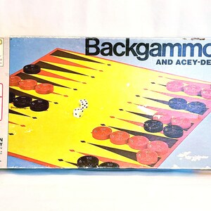 May include: Vintage Backgammon game box with a yellow playing surface, red and black checkers, and dice. The box reads "Backgammon and Acey-Deucy" and "Classic Game". The game is suitable for ages 7 to adult.