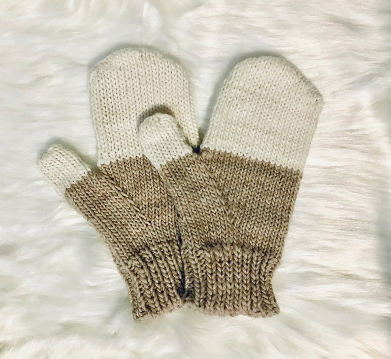Puede incluir: Un par de guantes tejidos con un esquema de dos colores. Los guantes son beige y marr&oacute;n, con el beige en la mitad superior y el marr&oacute;n en la mitad inferior.