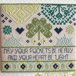 May include: Cross-stitch embroidery with a green shamrock design and the text "May your pockets be heavy and your heart be light".