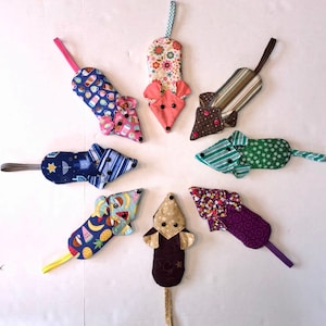 May include: A collection of handmade fabric toy mice in various colors and patterns. Each mouse features a different fabric design, including floral, striped, and patterned prints. The mice have button eyes and a fabric tail, with a loop for hanging.
