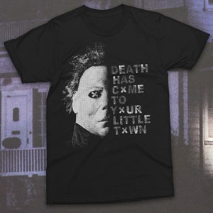 May include: Black t-shirt with a white graphic of a masked figure and the text "DEATH HAS CXME TO YXUR LITTLE TXWN".