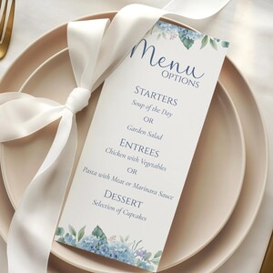May include: A menu card with the word "Menu" in elegant script, featuring floral accents and a list of food options. The card is tied with a white ribbon and placed on a blush-colored plate, with a gold fork and knife.