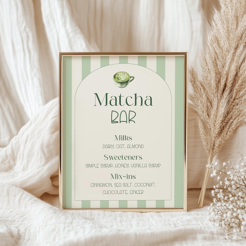 May include: A framed sign with a gold border and a green and white striped background. The sign reads "Matcha Bar" with a matcha cup illustration. Below, it lists milk, sweetener, and mix-in options.