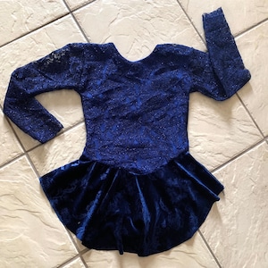 May include: A blue velvet and lace skating dress with long sleeves and a ruffled skirt.