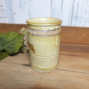 May include: A brown ceramic utensil holder with the words "Utensils" inscribed on the side.