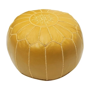 May include: Mustard yellow leather pouf with a round shape. The top features an embroidered starburst design. The pouf is stitched with a contrasting thread, creating a geometric pattern. This decorative ottoman is a stylish addition to any living space.