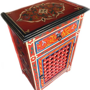May include: A red wooden nightstand with intricate hand-painted floral designs in yellow, blue, and green. The nightstand has a single drawer and a cabinet door with a lattice design.