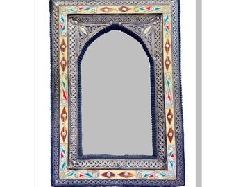 May include: An arched mirror with a decorative frame. The frame is navy blue with intricate silver-colored metalwork, cream-colored accents, and colorful details. The mirror has a rectangular shape with an arched top.