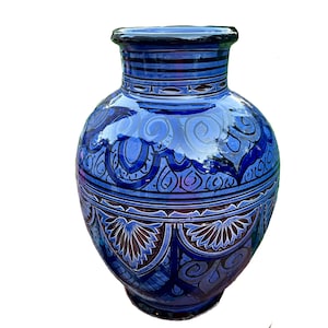 May include: A blue ceramic vase with intricate hand-painted designs in shades of blue and purple. The vase has a round body and a narrow neck.