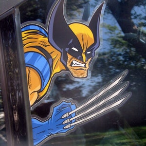Peut inclure: Un personnage de dessin animé de Wolverine jaune et bleu avec des griffes acérées, regardant férocement et prêt à attaquer. Le personnage est sur une vitre de voiture.
