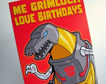 Può includere: Un biglietto rosso con il testo "ME GRIMLOCK LOVE BIRTHDAYS" in lettere gialle. Un'immagine di un robot dinosauro grigio e giallo con un simbolo Autobot rosso sul petto.