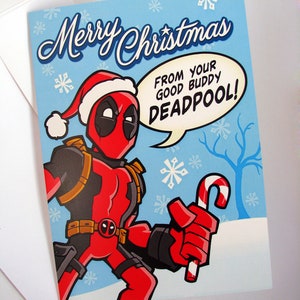 May include: A Christmas card with a cartoon Deadpool character wearing a Santa hat and holding a candy cane. The card has a light blue background with snowflakes and the text "Merry Christmas" and "From your good buddy Deadpool!"