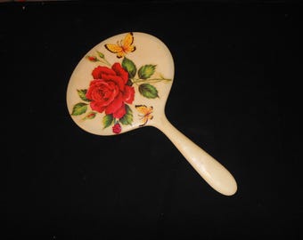Grande specchio a mano vintage degli anni '30 in celluloide con un grazioso dipinto di rose e farfalle sul retro - Lo specchio presenta alcuni difetti.