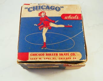 May include: A vintage square cardboard box for Chicago wheels featuring a blue background with a red-haired figure in a red dress skating. The text reads CHICAGO, wheels, and CHICAGO ROLLER SKATE CO. 4444 W. LAKE ST. CHICAGO 24 on the front panel.