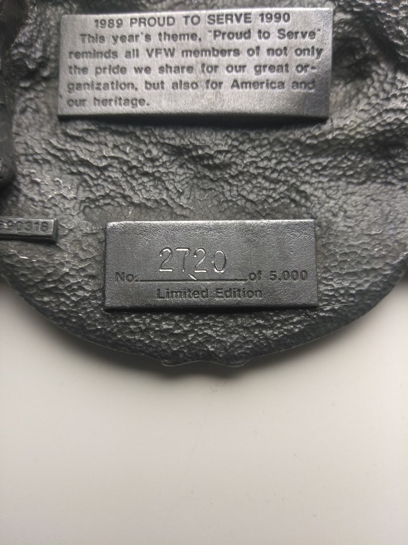May include: A silver metal plaque with the text "1989 PROUD TO SERVE 1990" and "This year's theme, 'Proud to Serve' reminds all VFW members of not only the pride we share for our great organization, but also for America and our heritage."  The plaque also has the text "No. 2720 of 5,000 Limited Edition".