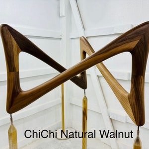 May include: A pair of wooden wall sculptures in the shape of a triangle with a natural walnut finish. The sculptures are attached to a metal rod with a gold tassel hanging from each.