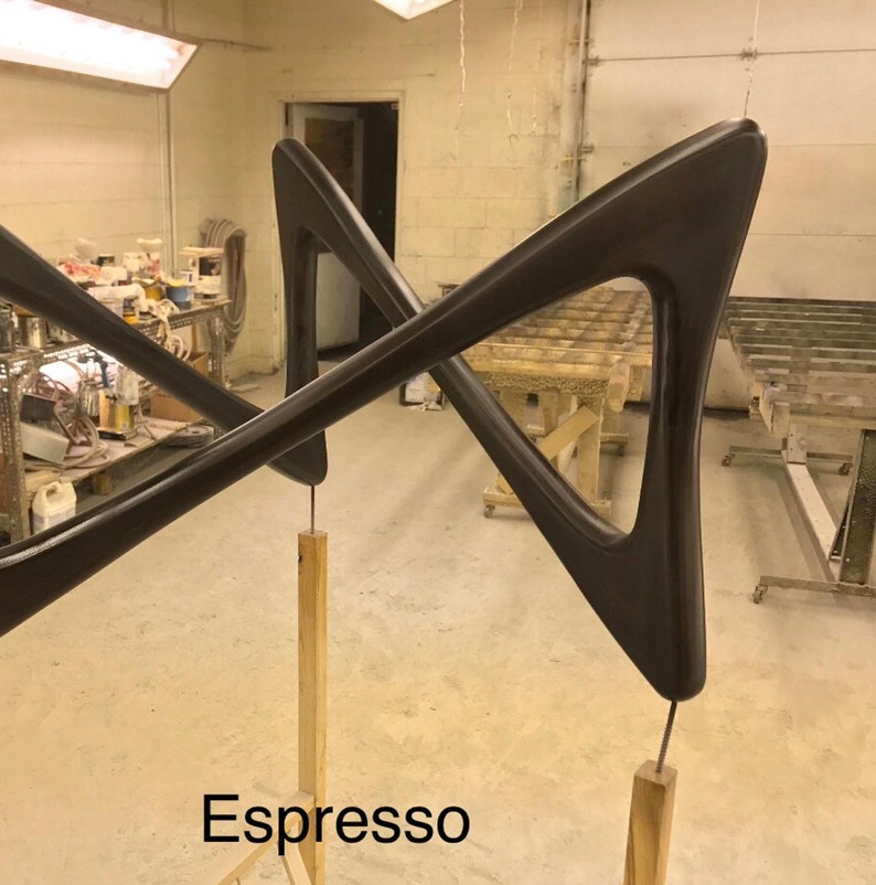 May include: Two dark brown wooden wall sculptures in the shape of a triangle with a rounded edge. The sculptures are mounted on wooden posts and are labeled "Espresso".