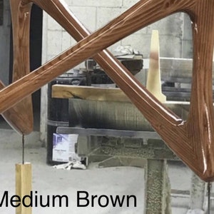 May include: Close-up of two wooden pieces of furniture in a medium brown color. The wood has a grainy texture and a glossy finish. The pieces are shaped like triangles and are joined together at their points. The text "Medium Brown" is visible at the bottom of the image.