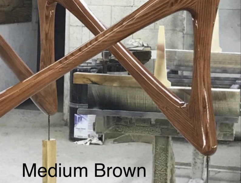 May include: Close-up of two wooden pieces of furniture in a medium brown color. The wood has a grainy texture and a glossy finish. The pieces are shaped like triangles and are joined together at their points. The text "Medium Brown" is visible at the bottom of the image.