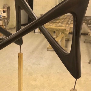 May include: A pair of dark brown wooden arms, shaped like a triangle, are connected in the middle and stand on two wooden posts. The arms are attached to the posts with screws. The text "Espresso" is written in white letters on the bottom of the image.