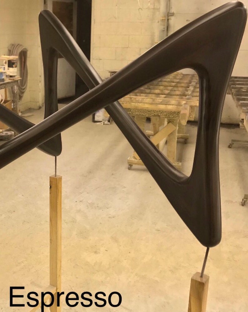 May include: A pair of dark brown wooden arms, shaped like a triangle, are connected in the middle and stand on two wooden posts. The arms are attached to the posts with screws. The text "Espresso" is written in white letters on the bottom of the image.